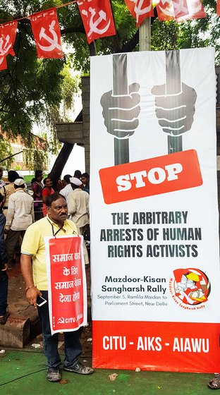 M.S. Shantkumar shuffles to the side to make way for a poster protesting the clamp down on civil liberties
