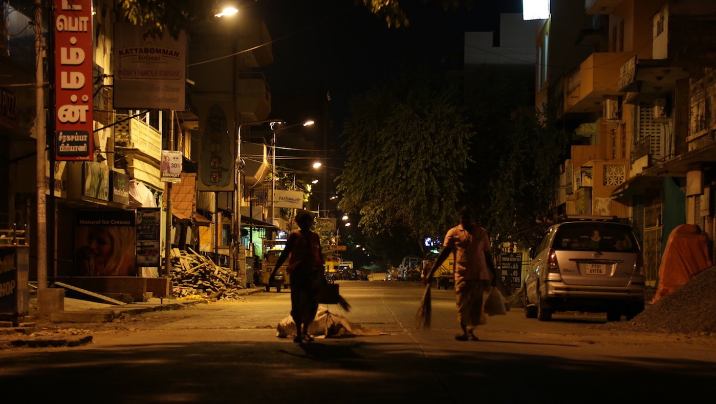 Women sweeping street at night