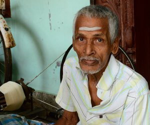 Old man in front of spinning wheel