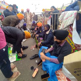 Unmindful of the dust, dirt and occasional rain, Jaswinder Singh Saini and Prakash Kaur, a couple from Delhi, perform sewa at Singhu – cleaning the dirty, muddied shoes of the farmers