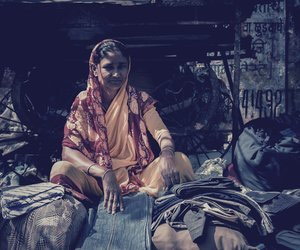Woman sitting next to pile of clothes